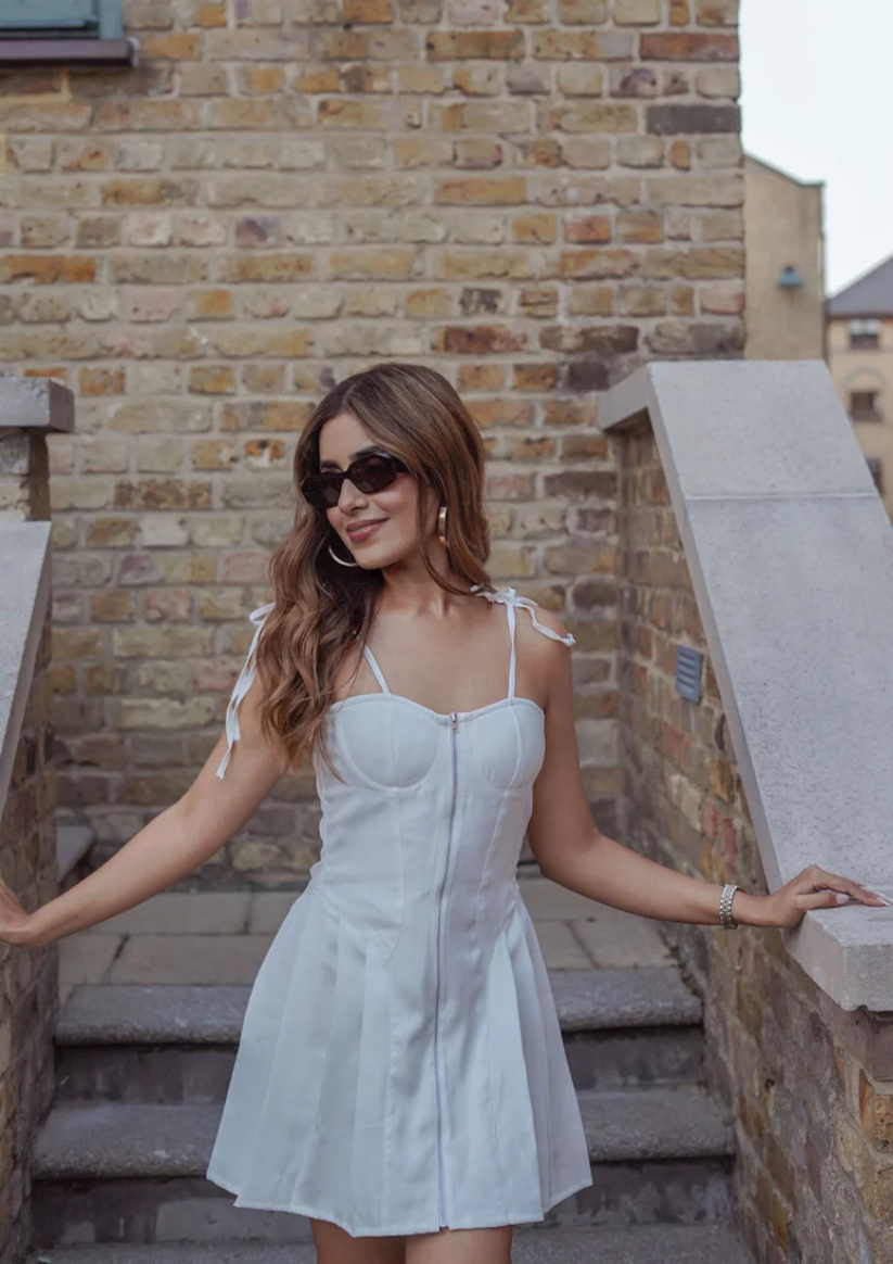 SioRaa sophisticated white pleated mini dress in banana crepe with fun front zip detail—perfect for a girls’ day out or relaxed cocktails.